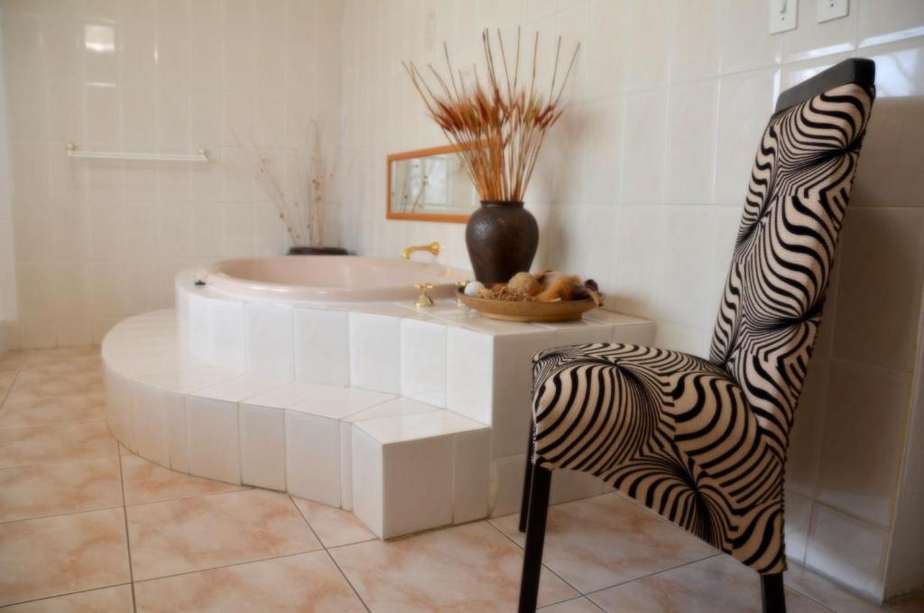 SasolburgAzrielle Guesthouse的带浴缸和斑马椅的浴室