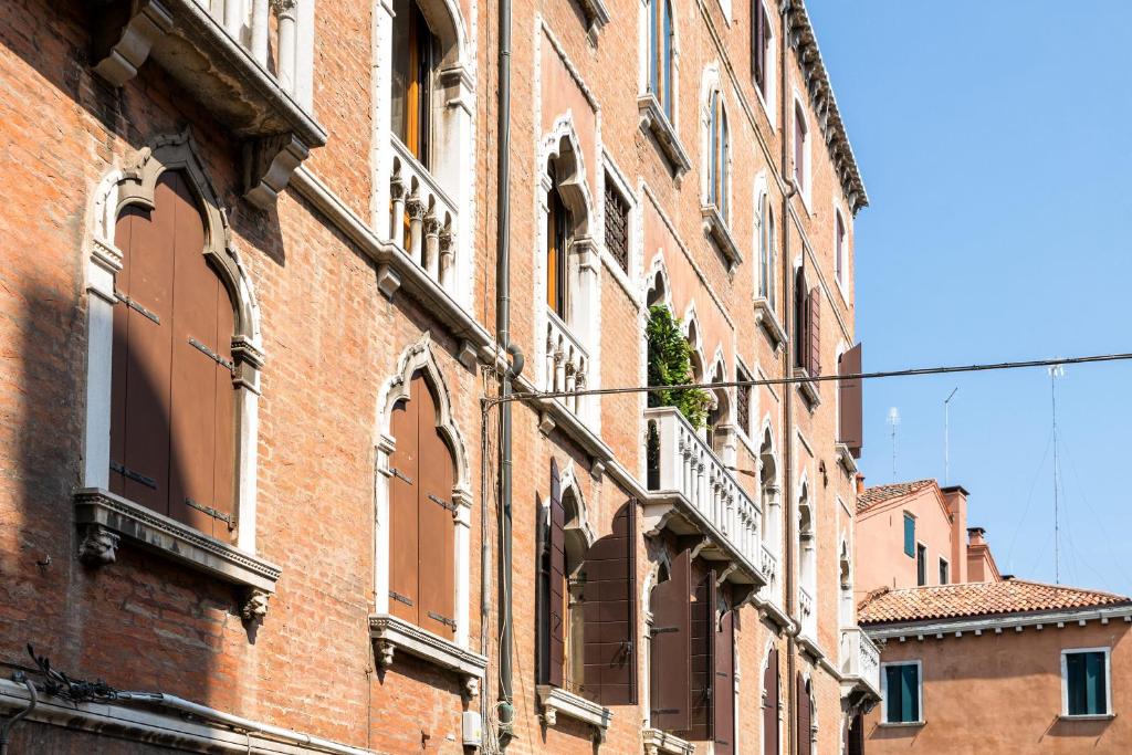 威尼斯San Zaccaria Apartment的红砖建筑,设有窗户和阳台
