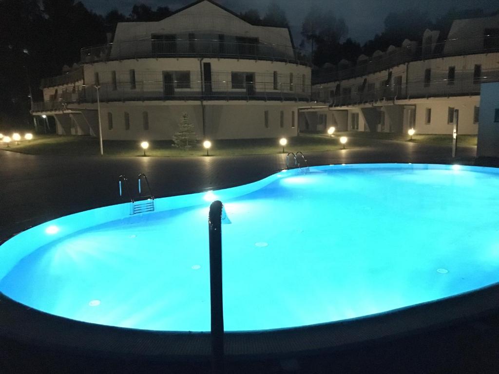 波别罗沃Apartament Silence Baltic Leśny的一座晚上点亮的大型游泳池