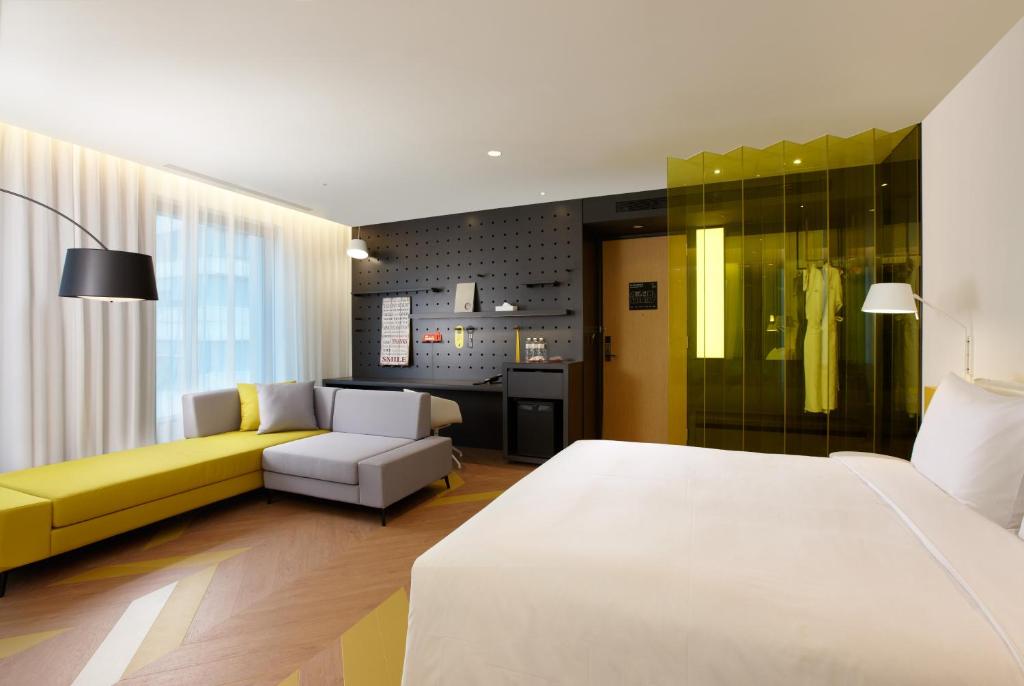 台北南港老爷行旅的卧室配有白色的床和黄色的沙发
