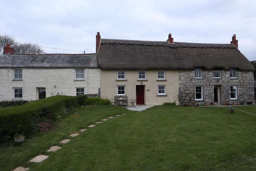 GwennapCornish Thatched Cottage的一座带草地庭院的古老石头房子