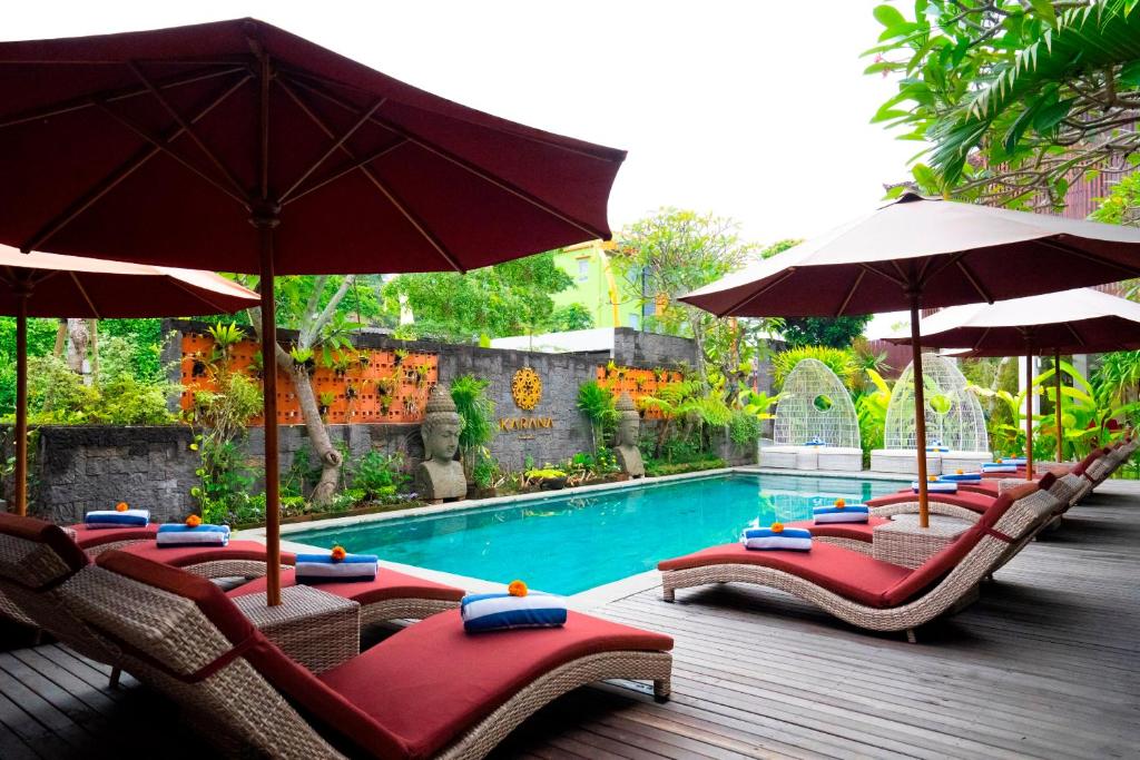 乌布Freddies Villas Ubud Bali的游泳池旁一排带遮阳伞的椅子