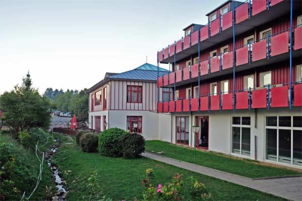 RundingFamilienhotel Reiterhof Runding的一座大建筑,在院子旁边,有红色的点缀