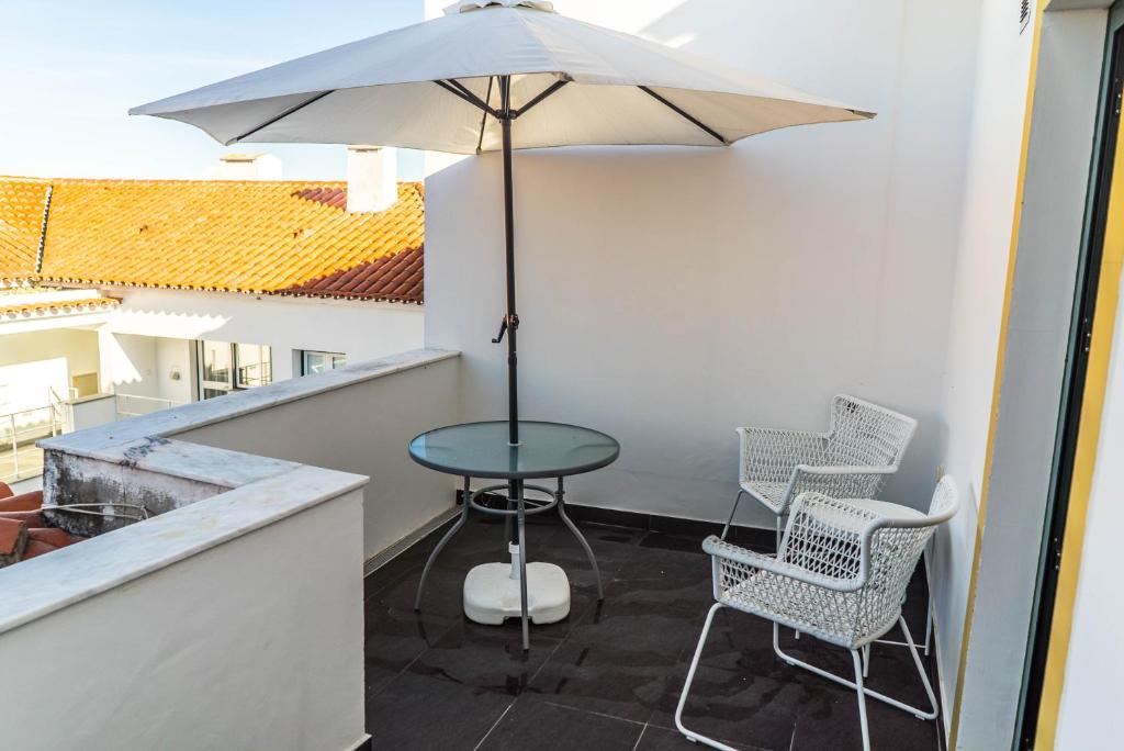 埃武拉Casa do Pateo II的庭院配有桌椅和遮阳伞。