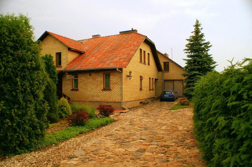 KunioniaiPrie upes的一座有红色屋顶和石头车道的房子
