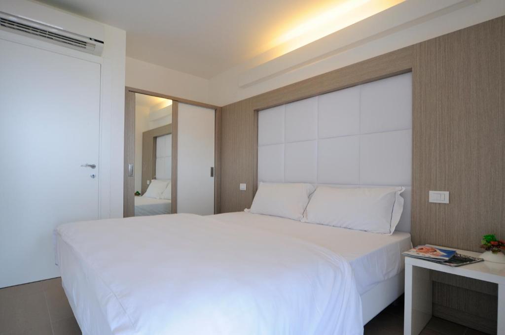 格拉多提齐安诺公寓式酒店的卧室设有白色的床和大窗户