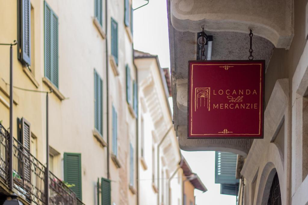 布雷西亚Locanda delle Mercanzie的挂在建筑物边的红色标志