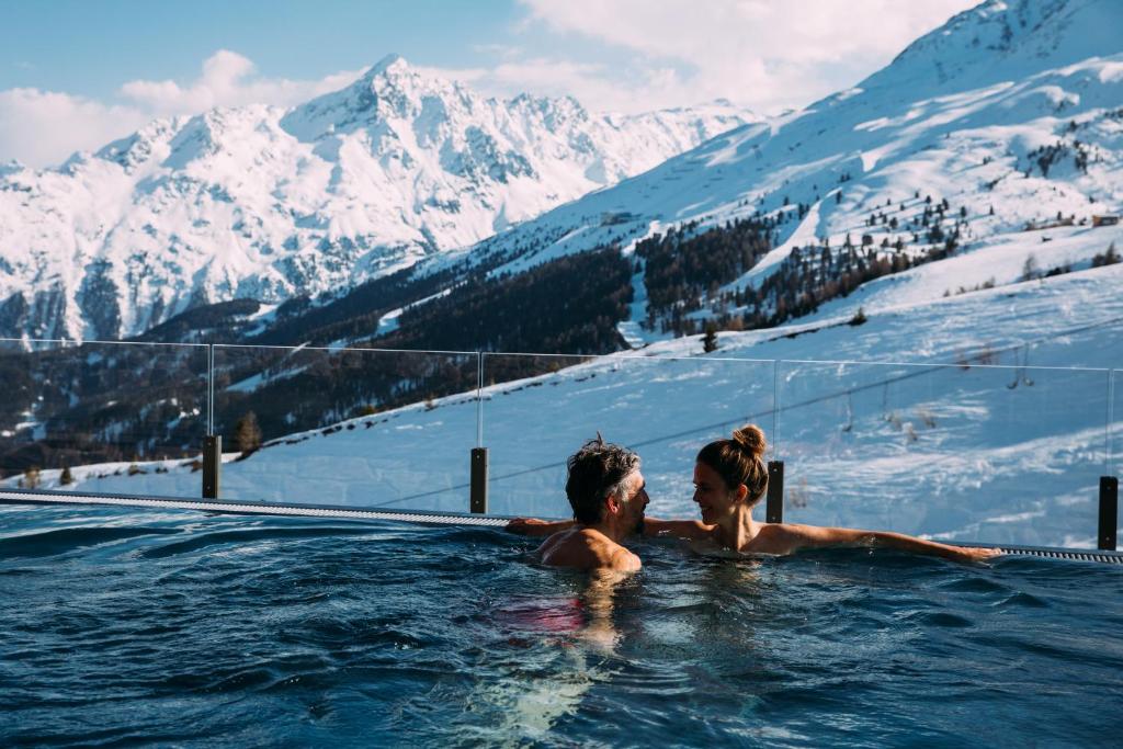 索尔登Hotel Enzian Hochsölden Superior的男人和女人在山地热水浴池里