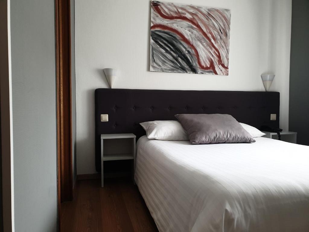 卢森堡亚夏酒店的卧室配有一张床,墙上挂有绘画作品