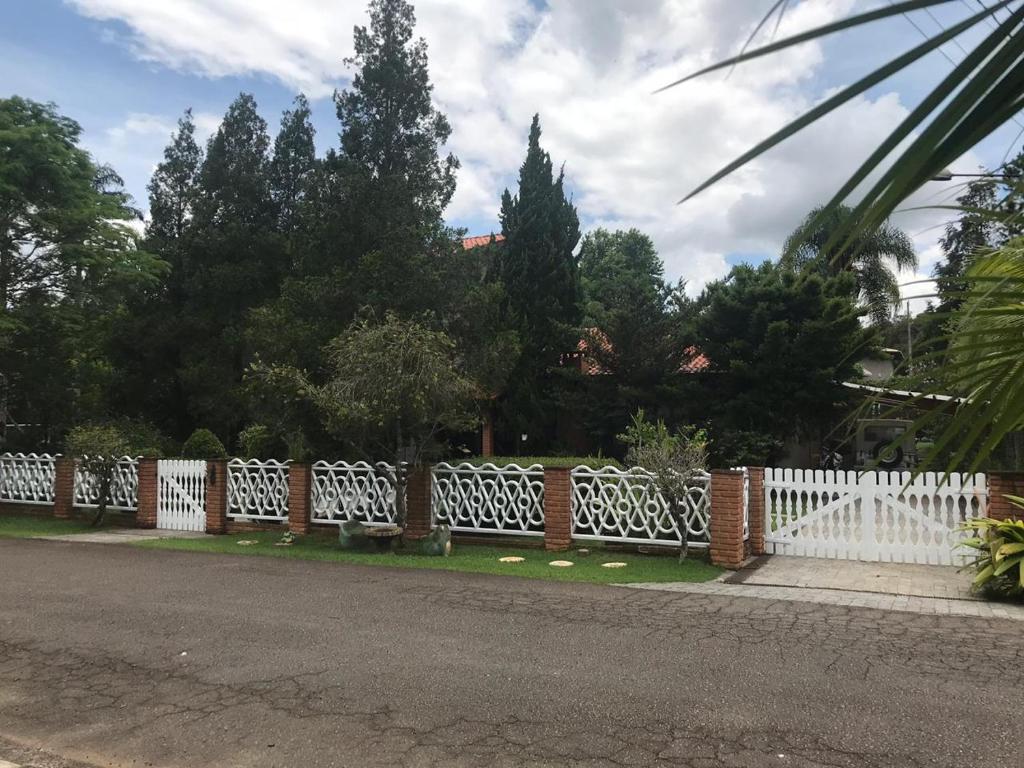 Joaquim EgídioCasa alto padrão em condomínio fechado - São Roque的树木繁茂的院子前的白色围栏