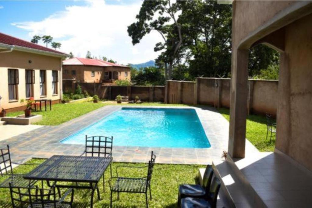 ZombaWadonda Suites的庭院内一个带椅子和桌子的游泳池