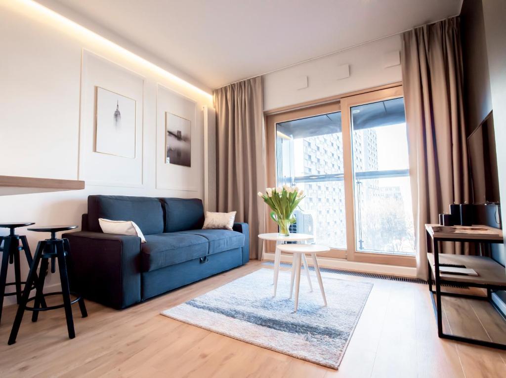 华沙MENNICA RESIDENCE PATRONUS Apartments的客厅设有蓝色的沙发和窗户。