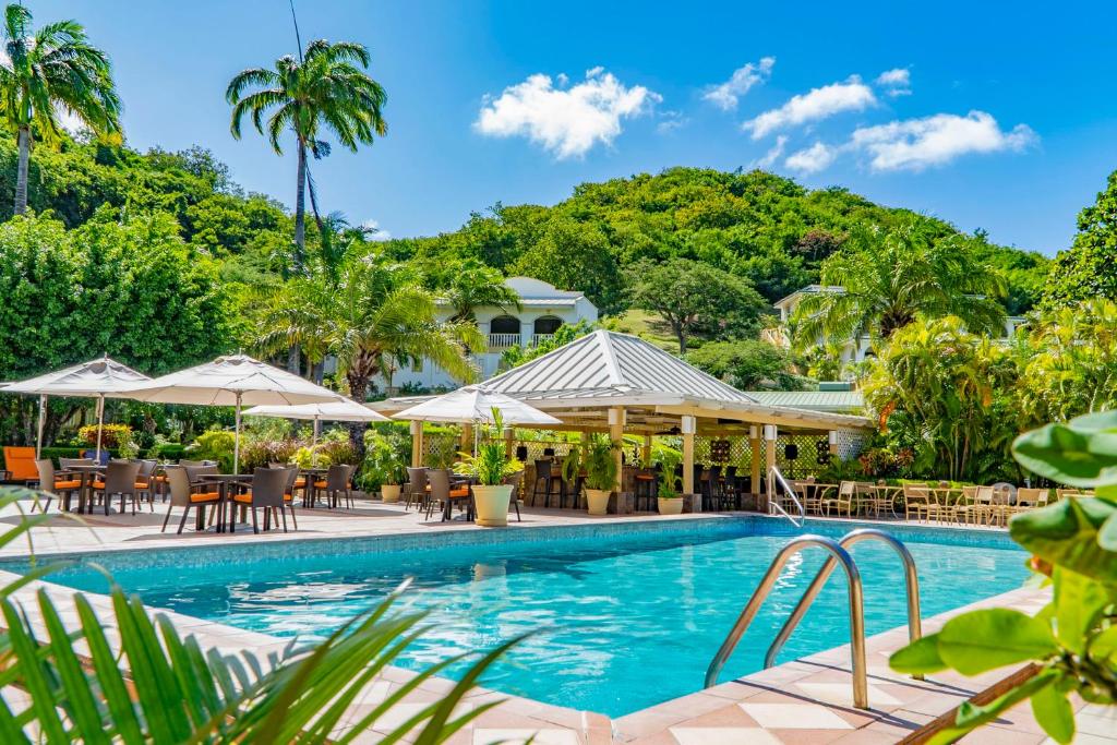 圣乔治蓝色地平线花园度假酒店的度假村的游泳池配有桌子和遮阳伞