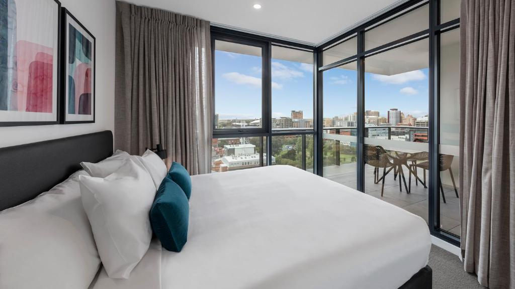 阿德莱德Avani Adelaide Residences的卧室设有白色的床和大窗户