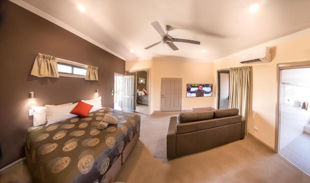 布罗肯希尔Broken Hill Outback Resort的一间卧室配有一张床、一张沙发和吊扇。