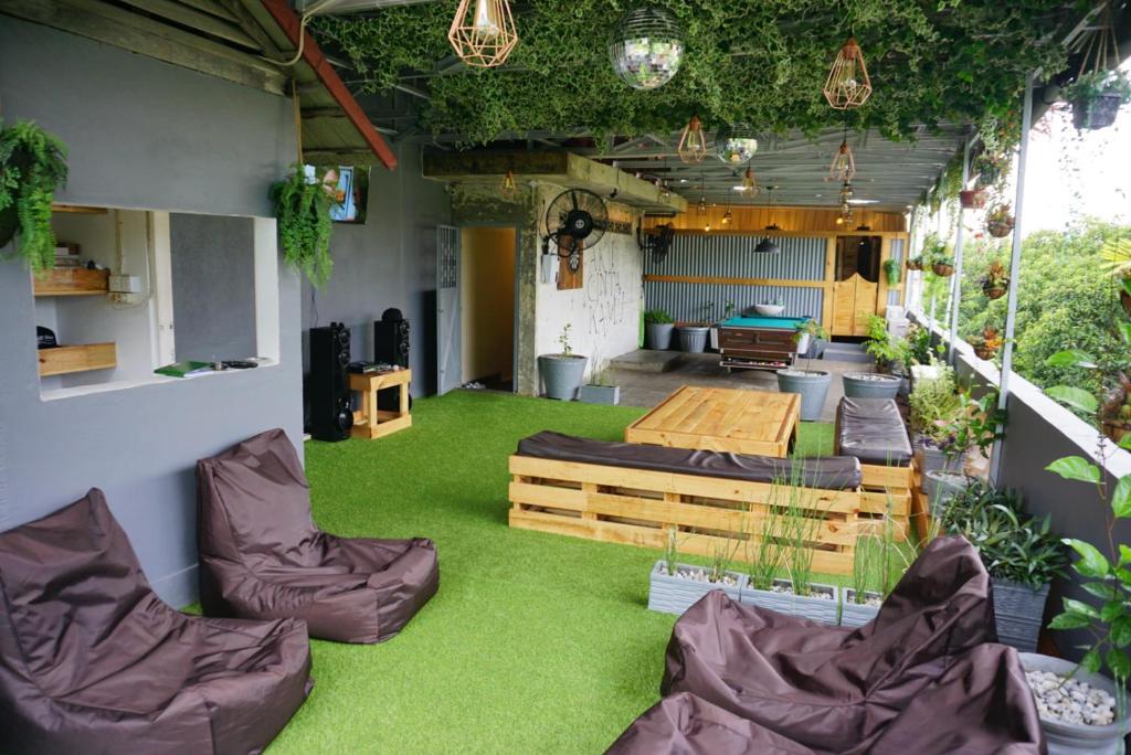 巴东Kokos Hostel Padang City的一间拥有绿色草地、家具和植物的房间