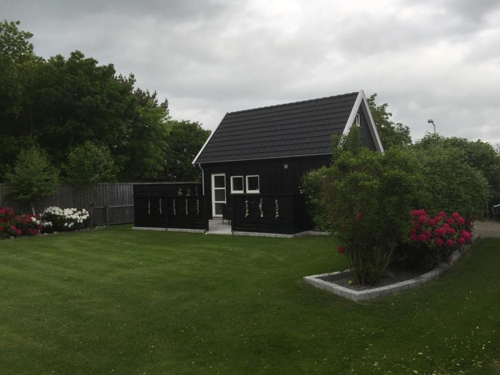 斯卡恩Skagen anneks的一座带绿色庭院的黑色小房子