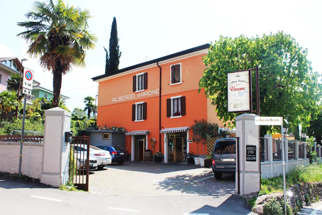 加尔达湖滨瓦拉内酒店的一座橙色的建筑,前面有汽车停放