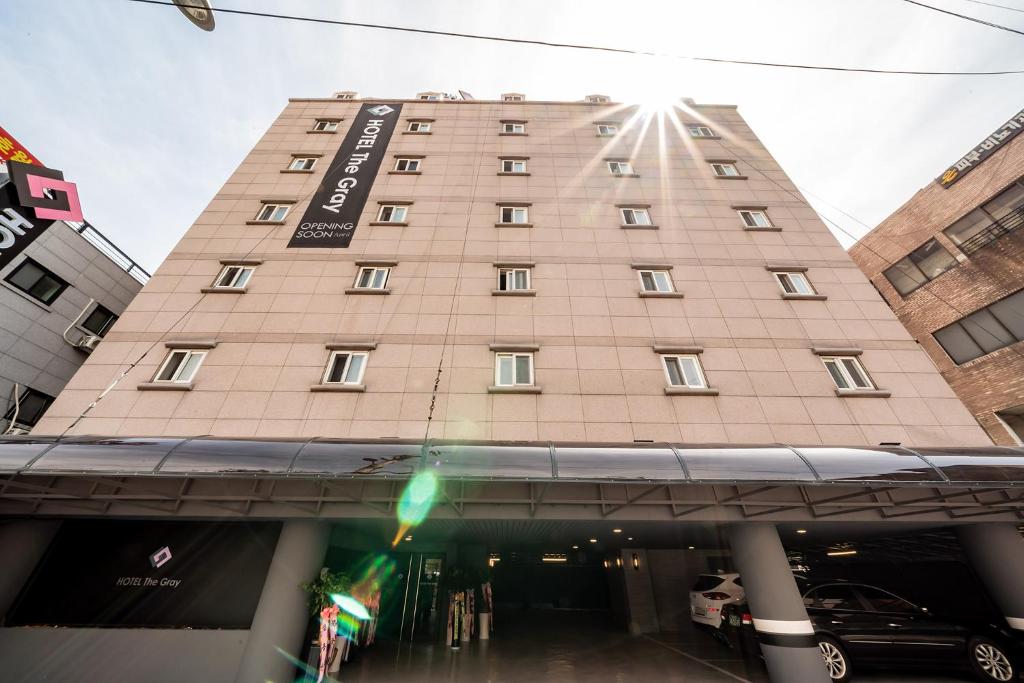 首尔THE GRAY HOTEL的一座高大的棕褐色建筑,上面有标志