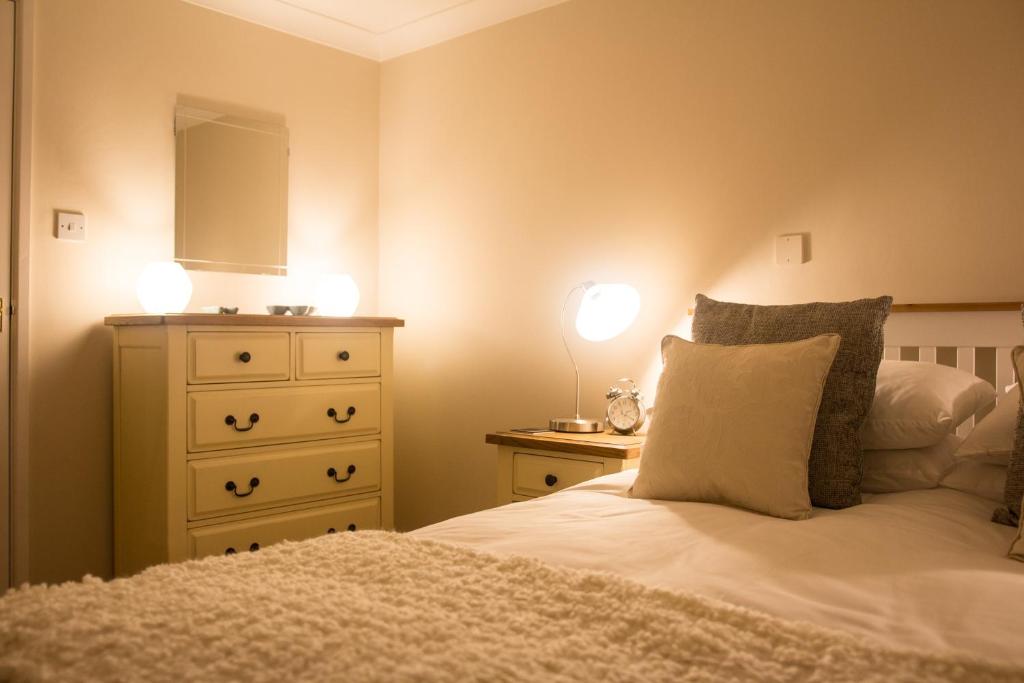 沙夫茨伯里Shaftesbury Modern Annexe的一间卧室配有一张床和一个带两个灯的梳妆台。