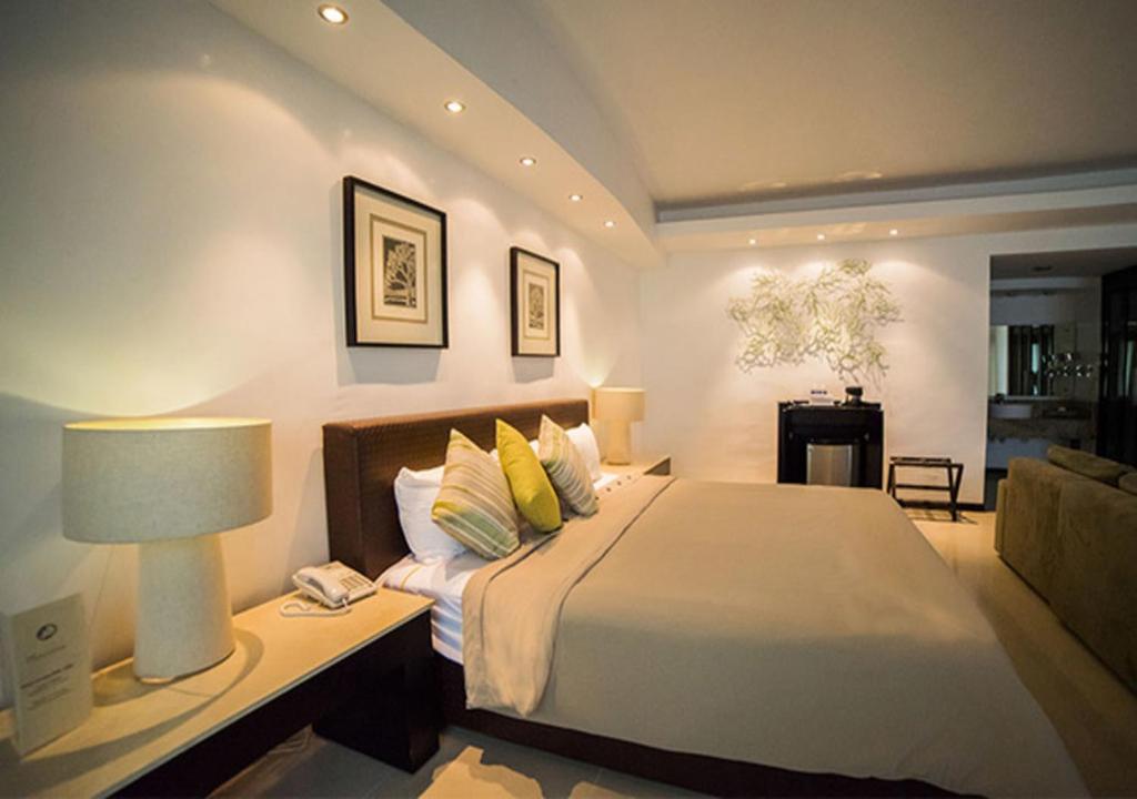 切图马尔大马龙酒店的一间卧室配有一张床和一张带台灯的桌子