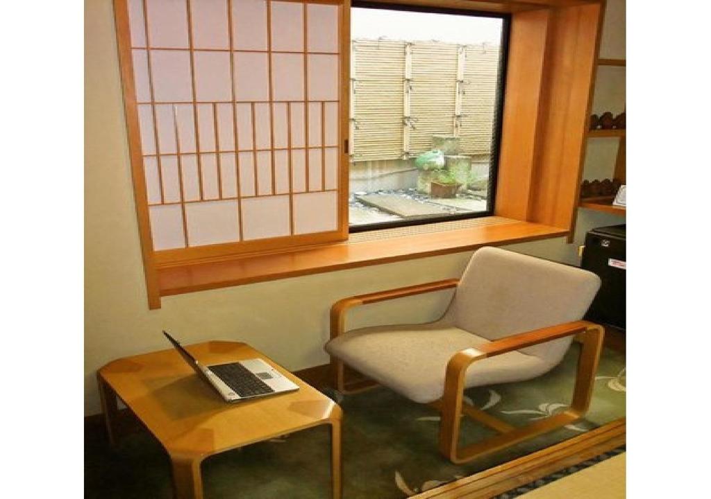 酒田市Wakaba Ryokan / Vacation STAY 29362的一间带椅子和一张桌子及一台笔记本电脑的房间