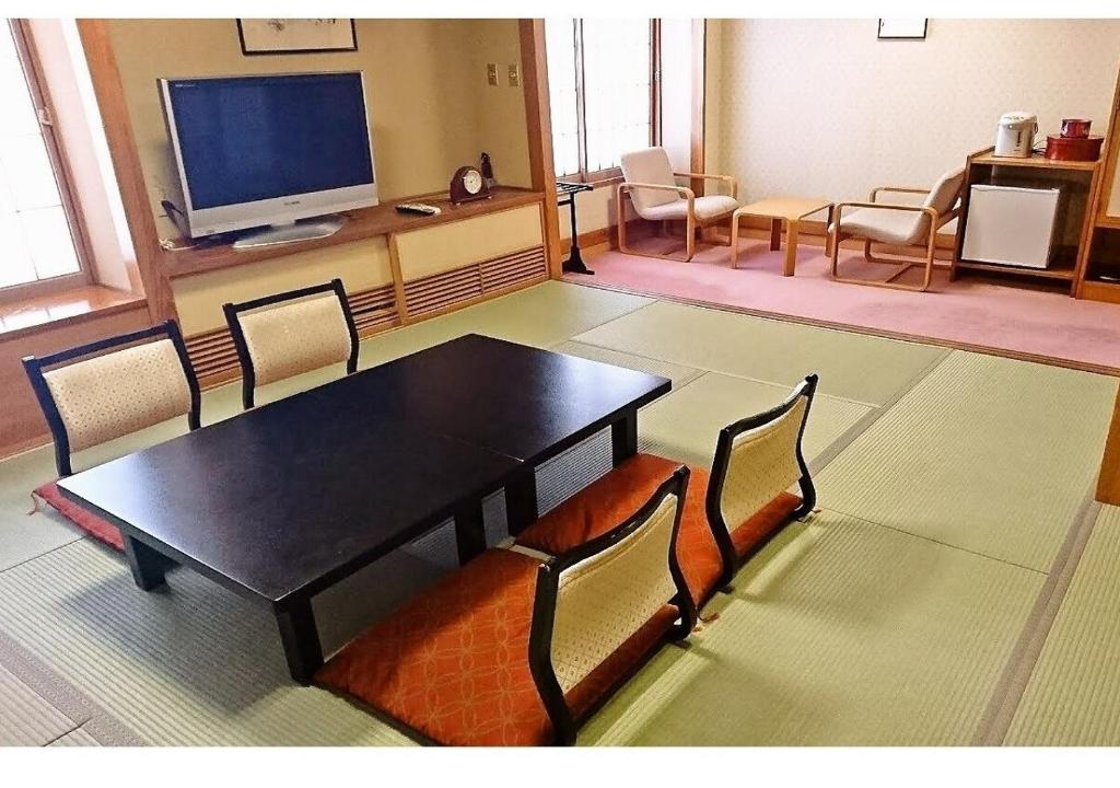 酒田市Wakaba Ryokan / Vacation STAY 29376的配有桌椅和电视的客房