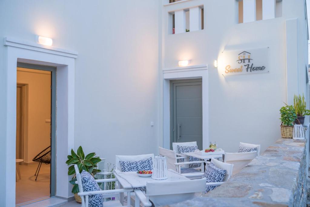 纳克索乔拉Sweet Home Naxos的一座配有白色桌椅的庭院和一座建筑