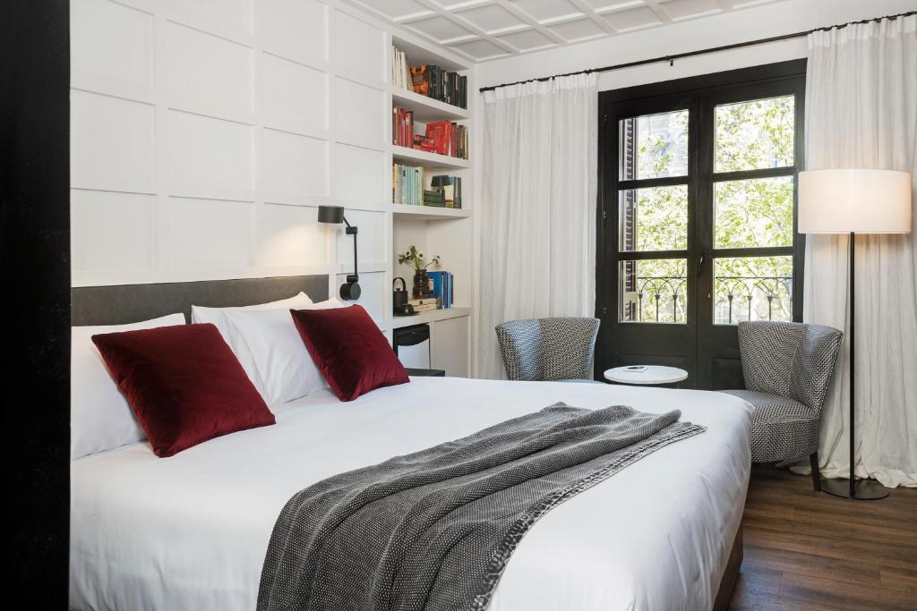 巴塞罗那Yurbban Ramblas Boutique Hotel的卧室配有带红色枕头的大型白色床