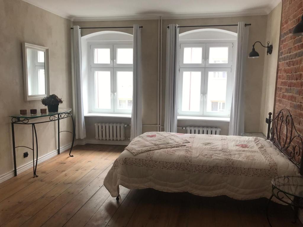 弗罗茨瓦夫Apartament Rustical的一间卧室设有床铺、两个窗户和砖墙