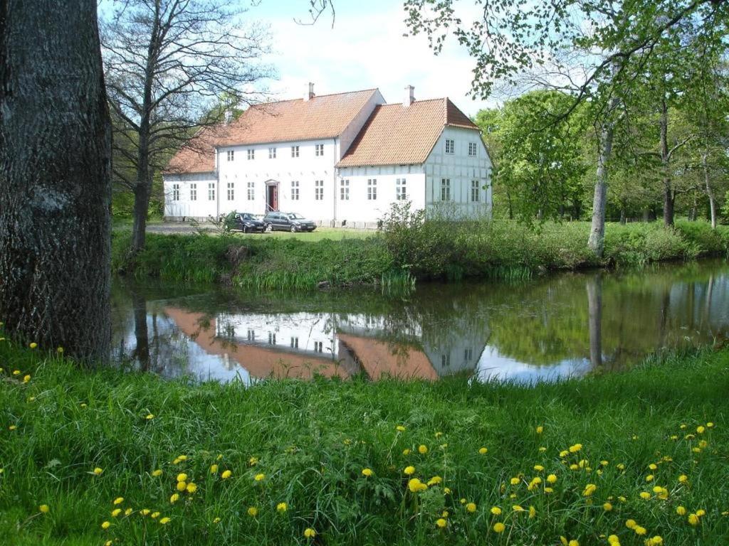 腓特烈港Lerbæk Hovedgaard的水体旁的白色大建筑