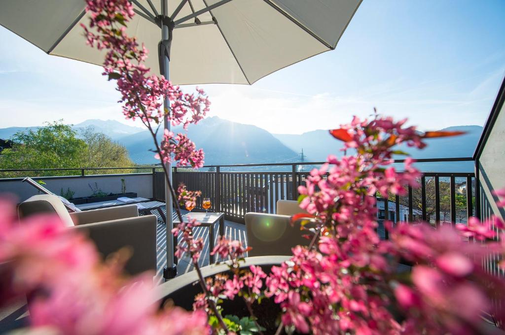 蒂鲁罗Hotel Zum Tiroler Adler的阳台配有桌椅和粉红色的鲜花