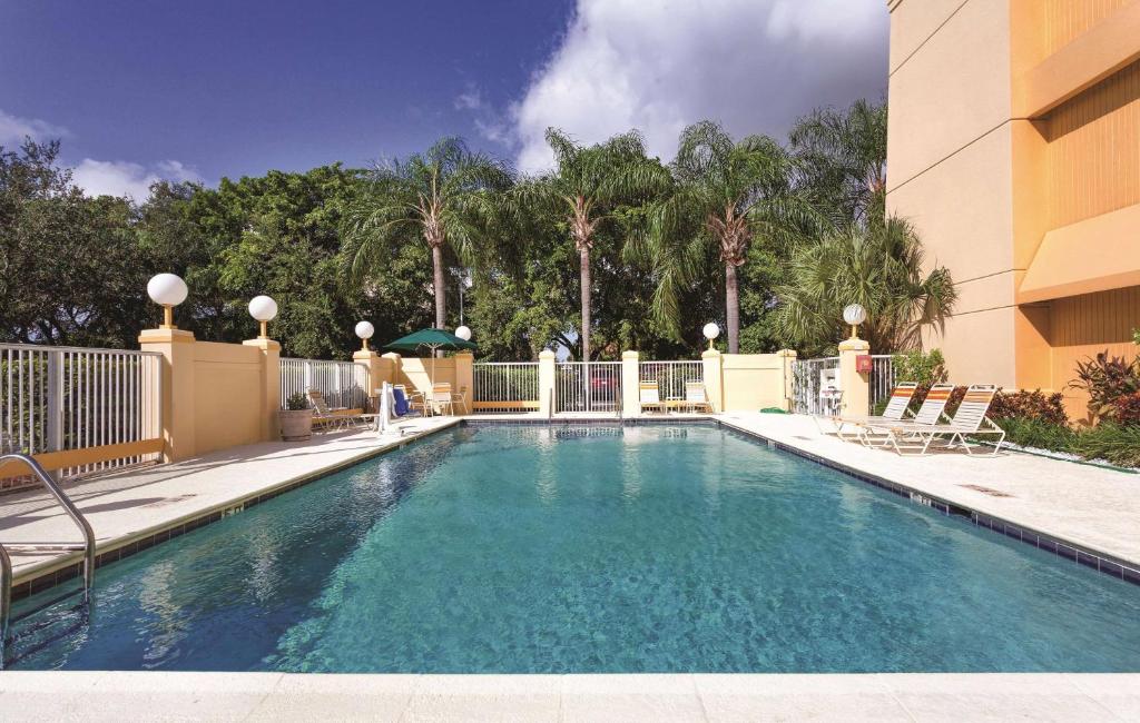 迈阿密迈阿密机场东拉昆塔套房酒店的一座带椅子的建筑前的游泳池