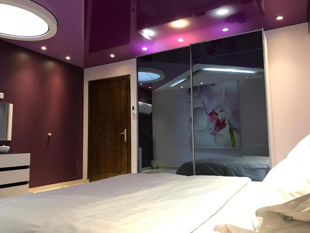 塔伊夫Deluxe Furnished Apartments的卧室设有白色的床和紫色天花板。