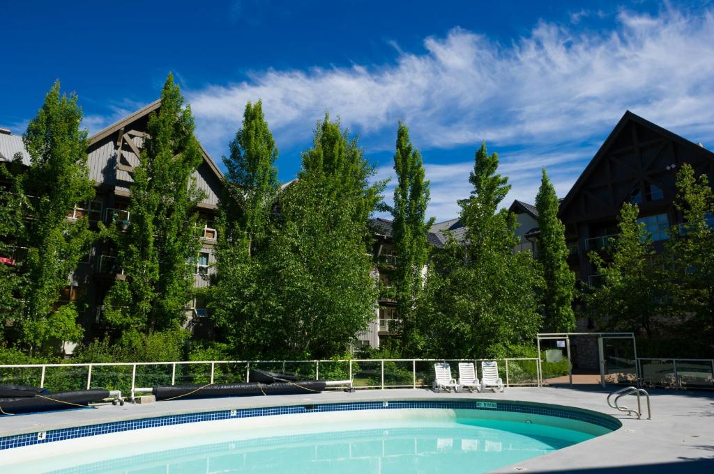 惠斯勒维斯基杰克阿斯朋兹酒店的一座树木繁茂的建筑前的游泳池