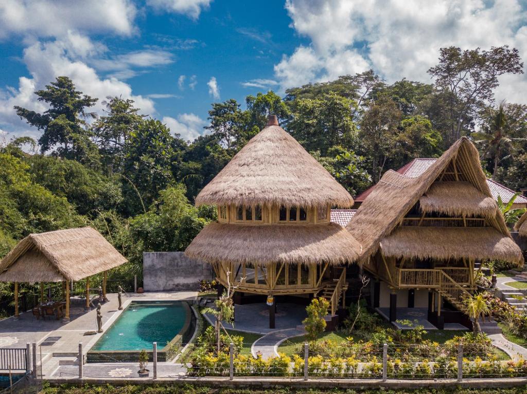 乌布Le Sabot Ubud的一座带游泳池和茅草建筑的度假村