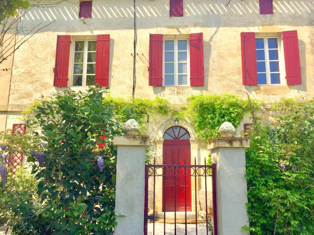 PineuilhLA CARRETERIE - Les Gîtes的一座带红色百叶窗和门的旧房子
