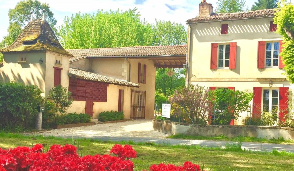 PineuilhLA CARRETERIE - Maison de Famille{s}的红色门的房子和红色花的院子