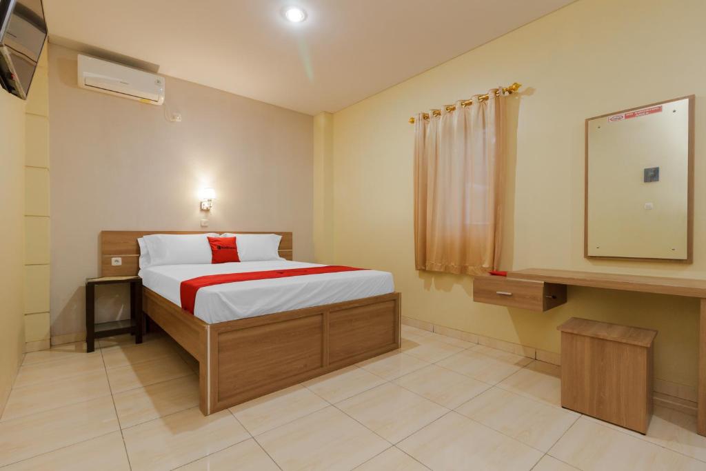 美娜多RedDoorz Plus near Pantai Malalayang Manado的一间卧室配有一张床和一台电视。