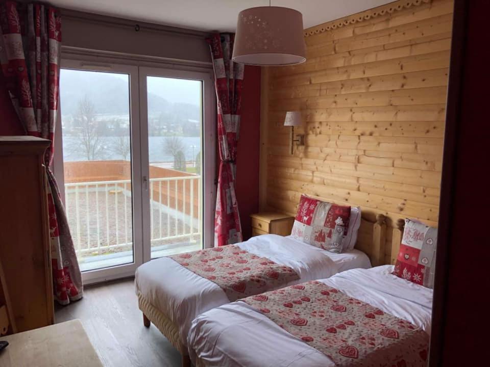 热拉梅Le Ptit Hotel du Lac的一间卧室设有两张床和大窗户
