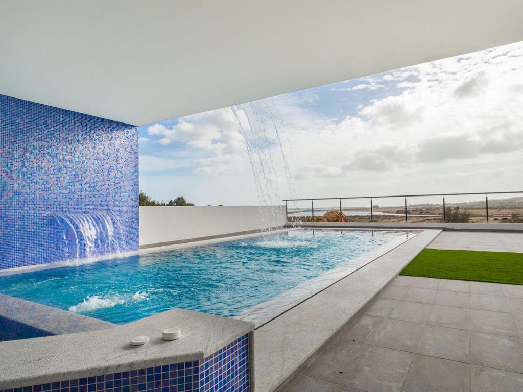 阿尔沃尔Villa Ria Alvor- Swimming pool & Jacuzzi的一座建筑顶部的游泳池,设有瀑布
