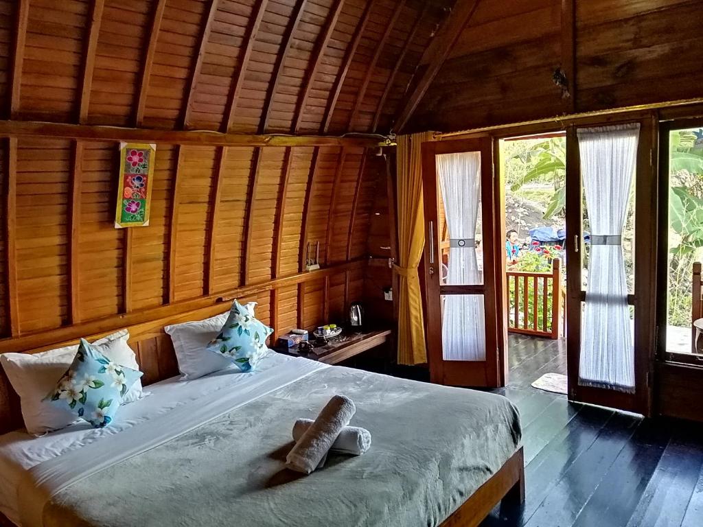 珀尼达岛Ginanthi Cottage的一间带一张大床的卧室,位于带木墙的房间