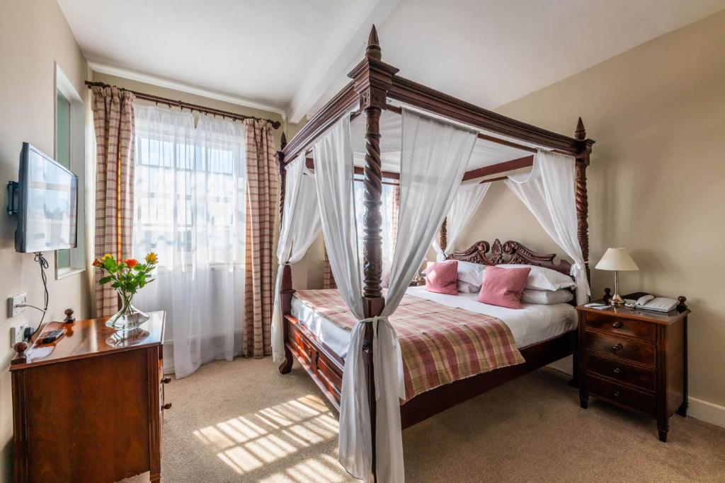莫顿汉普斯泰德白鹿酒店 的卧室配有带粉红色枕头的天蓬床