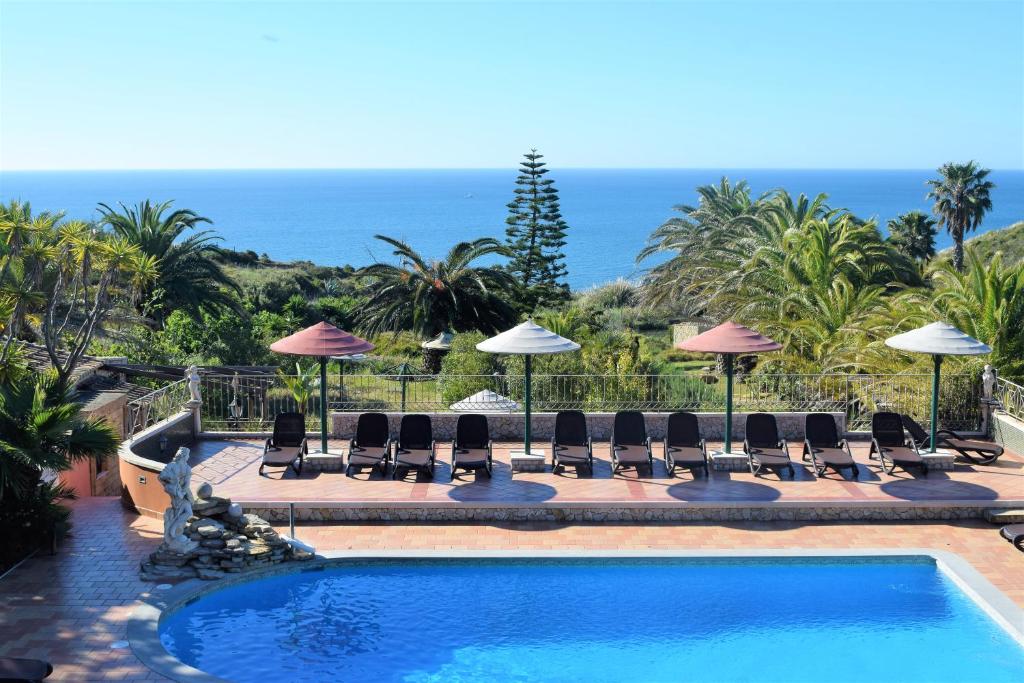 卢斯Quinta do Mar - Country & Sea Village的一个带椅子和遮阳伞的游泳池以及大海