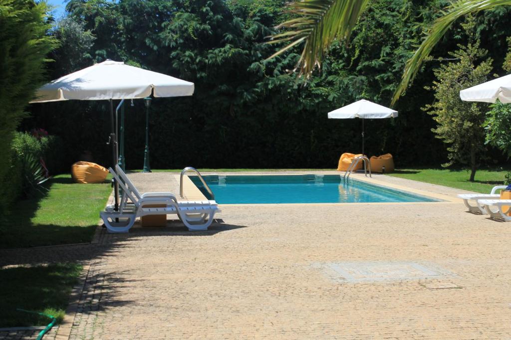 布拉干萨Quinta da Boa Ventura的一个带两把椅子和遮阳伞的游泳池