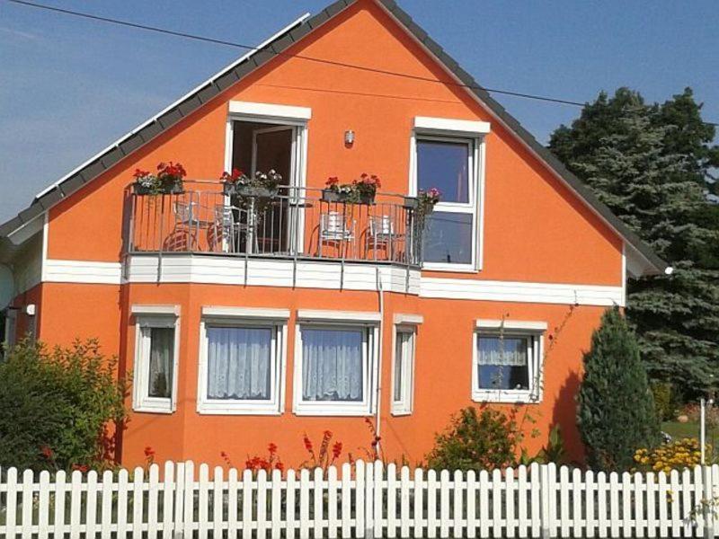Neu MukranRügen Fewo 284的一座橙色房子,前面有白色的围栏