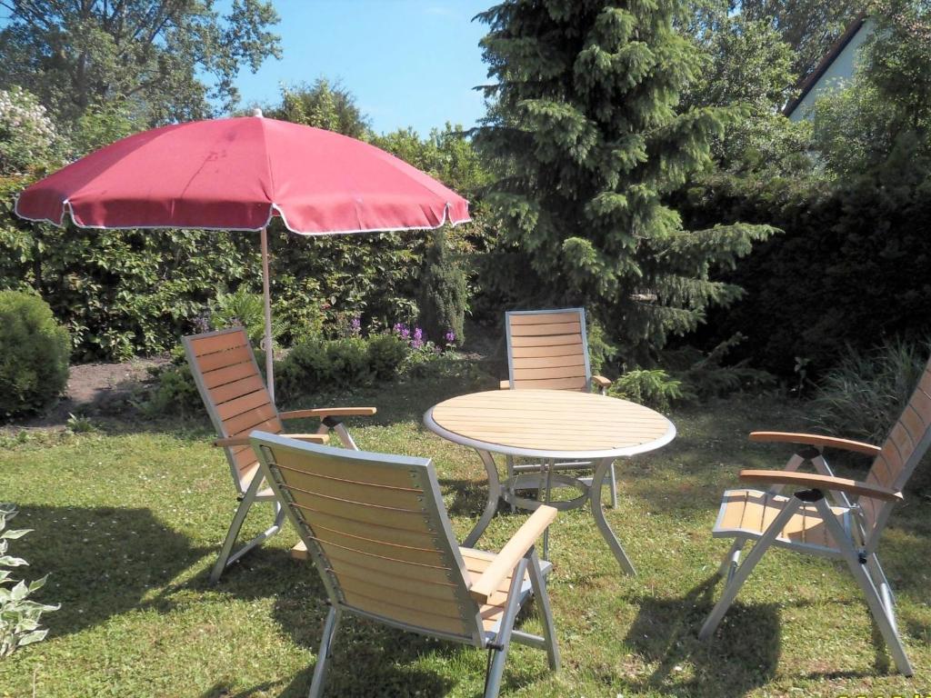 奥斯特巴德里克Modern Apartment in Rerik with Garden的三把椅子和一张带红伞的桌子