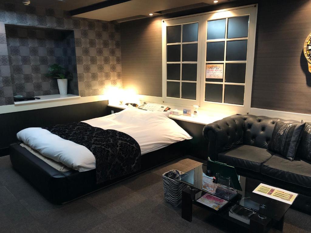 八王子市ホテル フェリエ hotel for adults的一间卧室配有一张床、一张沙发和一张桌子