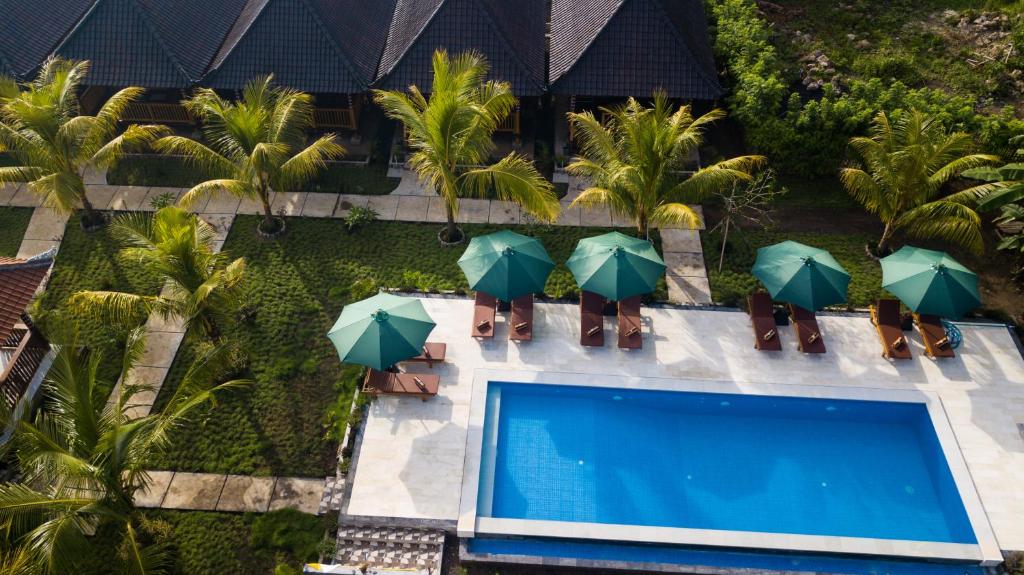 珀尼达岛Ruji Ananta Cottage的享有带绿伞的游泳池的顶部景致