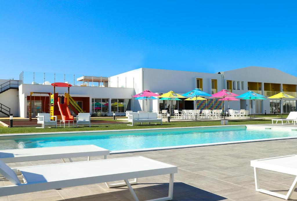 佩尼契RIDE Surf Resort & Spa的一个带椅子和遮阳伞的游泳池和一个游乐场